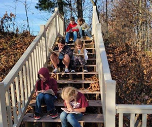 Students sitting on outside stairs reading books