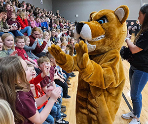 School mascot giving students high-fives in the gym