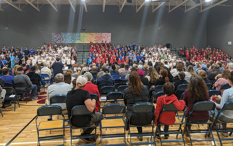 Students and families in gym wearing red, white, and blue