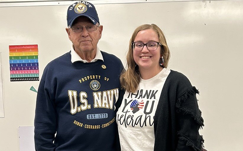 U.S. Navy official next to a woman wearing a Thank You Veterans t-shirt